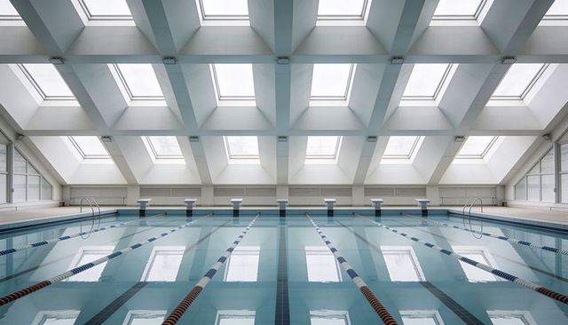 Minimalist indoor lap pool featuring skylights, symmetric lanes and starting blocks