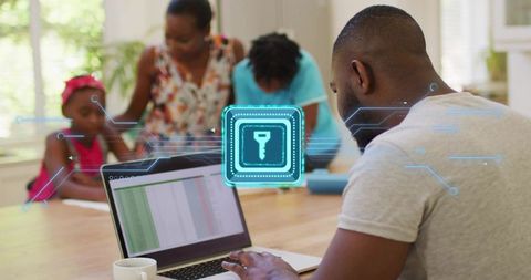 Working parent securing online data while using laptop at home with family in background