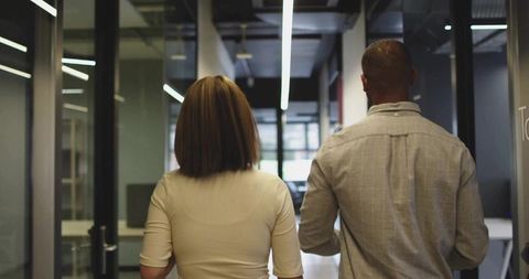 Two Professionals Walking in Modern Office Corridor