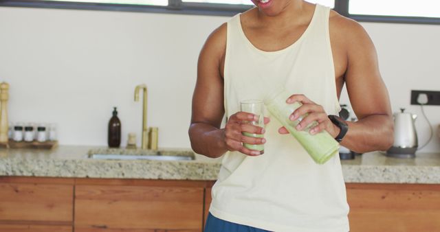 Fit african american man cooking, drinking healthy green smoothie. healthy active lifestyle and fitness at home.