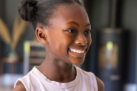 Beaming african youth smiling side profile in bright interior with natural buns