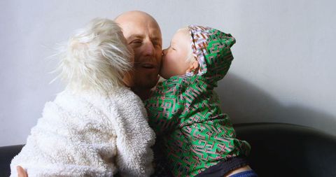 Father enjoying affectionate kisses from loving children at home