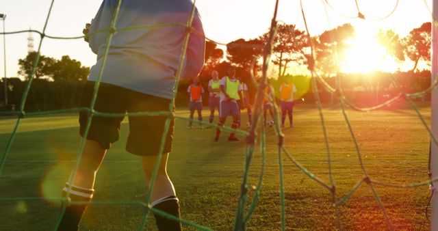 Youth soccer players practicing on a field during sunrise. This can be used for portraying active lifestyles, sports training, team-building activities, and athletic youth engagement.