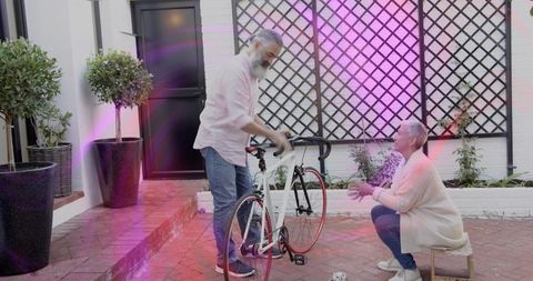 Mature couple preparing road bike on brick patio, sharing outdoor moment and conversation