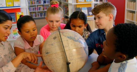 Diverse Children Learning Geography in School Library with Teacher