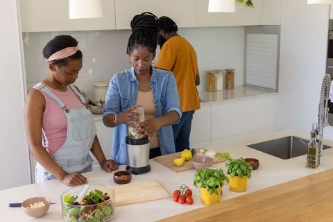 African american family cooking together in bright modern kitchen blending fresh food