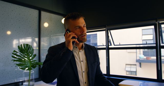 Business Person Talking on Phone by Office Window - Download Free Stock Images Pikwizard.com