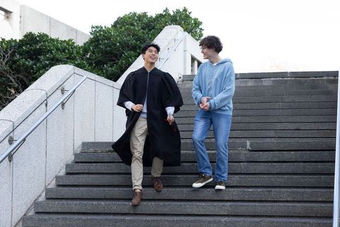 Graduating student walking with friend on campus stairs celebrating success and friendship