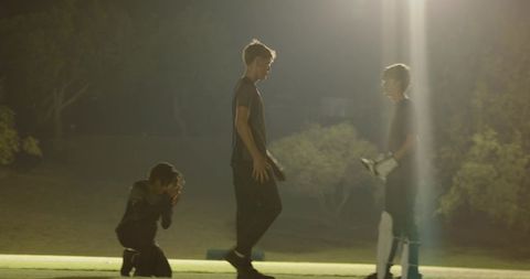 Diverse night cricket players exchanging gloves under floodlights showing teamwork