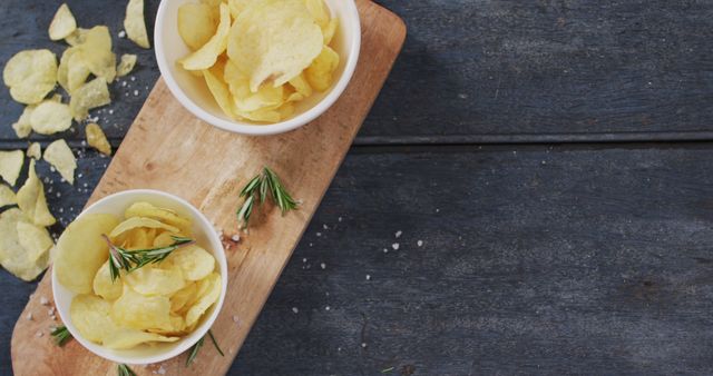 Close up view of two bowls of potato chips on wooden tray with copy space on wooden surface. food and snack concept