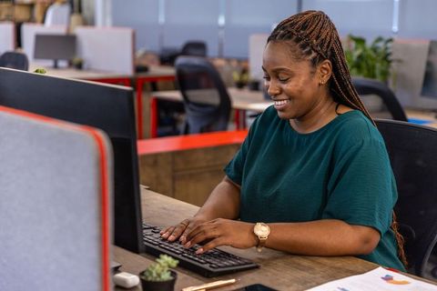 Smiling Woman Working at Computer Desk in Modern Office