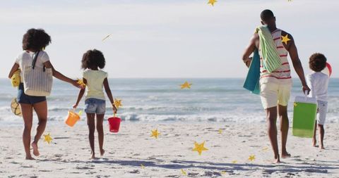 Family walking to ocean on sunny beach with towels, buckets and cooler, summer vacation, sand shorel