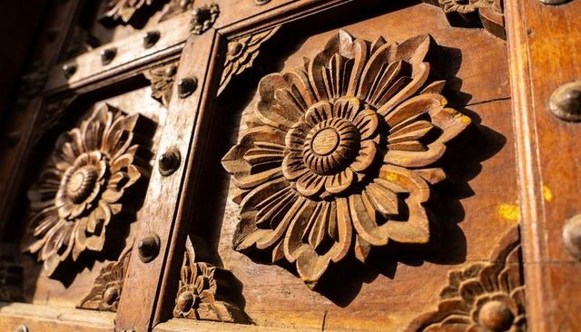 Ornate hand-carved wooden rosette panel showing warm patina and floral relief