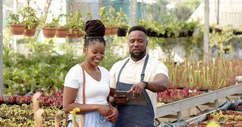 Couple Discussing Plant Care at Lush Greenhouse