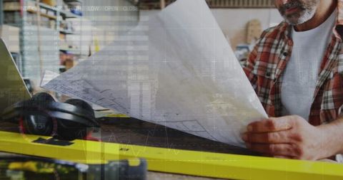Carpenter analyzing blueprints with digital data overlay