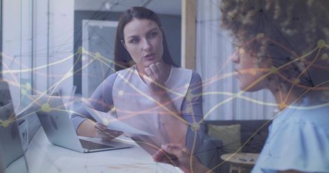 Businesswomen Collaborating Over Data in Modern Office