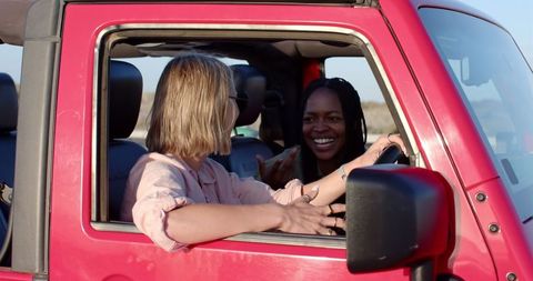 Friends enjoying road trip adventure in red car