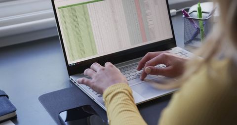 Businesswoman Analyzing Data Spreadsheets on Laptop at Home Office