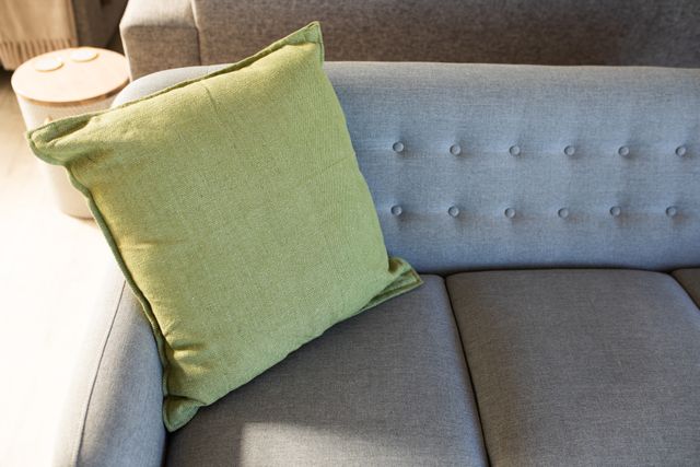 Green cushion placed on grey sofa in modern living room. Ideal for articles or blogs about home decor, interior design trends, and modern living spaces. Perfect for showcasing comfortable and stylish home furnishings.