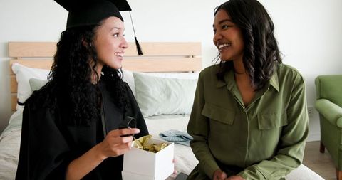 Graduation Celebration at Home: Friends Smiling and Exchanging Gift