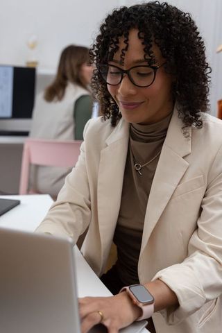 Diverse female professional working on laptop in modern coworking space, focused