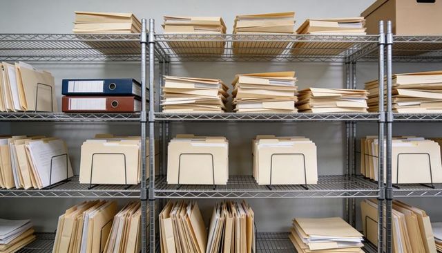 Metal wire shelving with organized manila folders and binders in records archive room