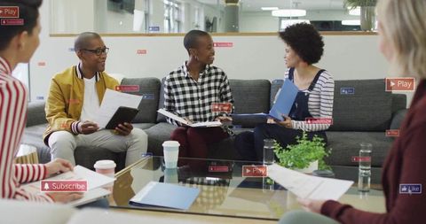 Diverse creative team collaborating in modern lounge meeting with documents and coffee