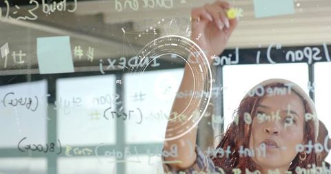 Young professional woman brainstorming on glass board with code and futuristic hud overlay