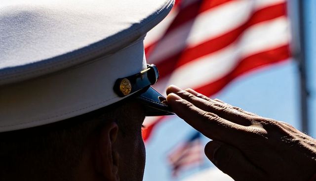 Uniformed service member saluting american flag at memorial ceremony white dress cap