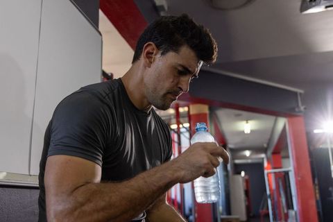 Muscular man resting and hydrating with water bottle after intense gym workout