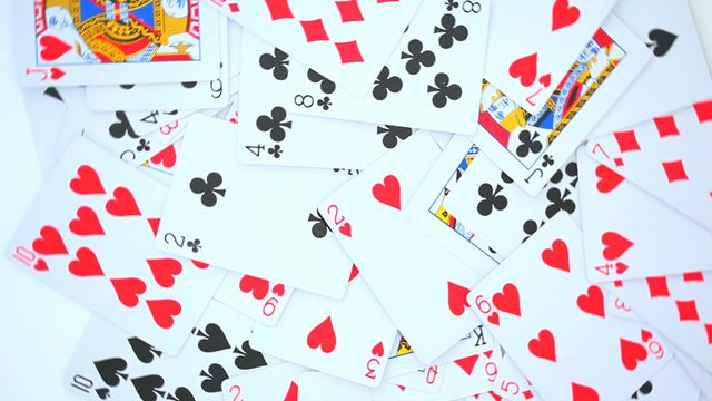 Scattered playing cards spread out on a white background. Suitable for themes related to gambling, gaming, leisure activities, casino games, and recreational hobbies. Ideal for websites, blog posts, promotional materials, or educational content involving card games.