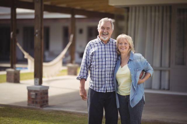 Portrait of senior couple smiling while standing outside their house