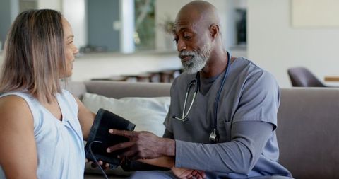 African american nurse checking blood pressure of mature woman during home care visit