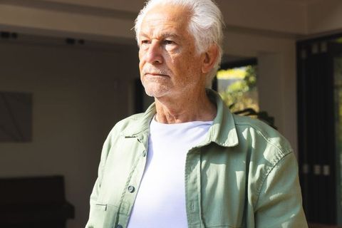 Senior Man Reflecting by Sunlit Doorway in Modern Home