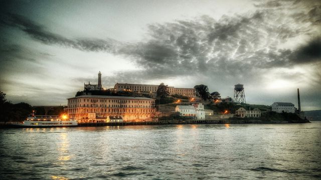Captured at sunset, this photograph showcases the iconic Alcatraz Island as its structures are lit up against the evening sky. Ideal for use in travel blogs, historic site features, or tourism promotions highlighting San Francisco Bay's attractions.