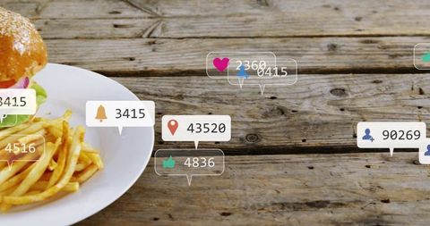 Burger and fries on wooden table with social media notification icons and copy space