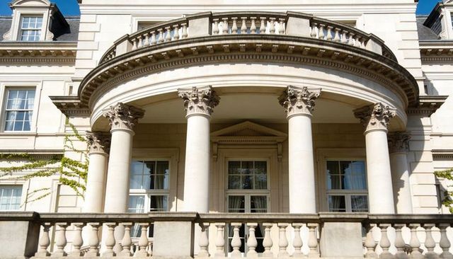 Neoclassical mansion facade showcasing semicircular balcony, corinthian columns, balustrade
