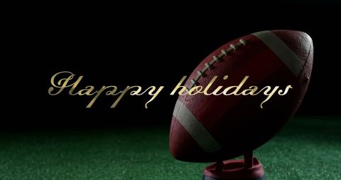 Holiday greeting with rugby ball on stand against dark background