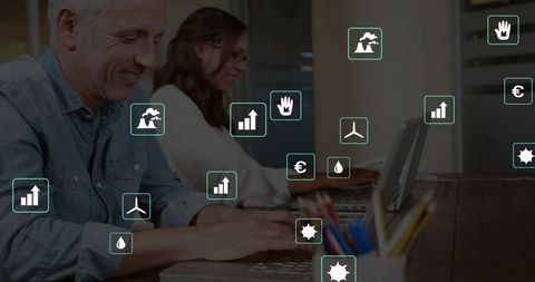 Mature professionals collaborating at coworking table with green energy and analytics icons