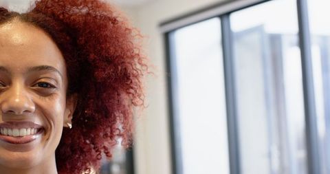Smiling Woman with Curly Hair Near Window Blinds