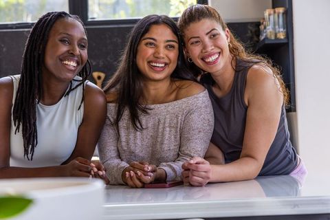 African american and diverse friends leaning on countertop smiling in natural light