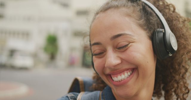 Happy biracial woman in city, wearing headphones and smiling - Download Free Stock Photos Pikwizard.com