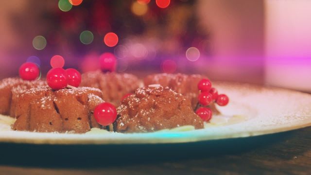 Festive holiday cakes adorned with powdered sugar and red berries are showcased on a wooden table, with colorful bokeh lights in the background. This atmospheric setting evokes warmth and holiday spirit. Ideal for Christmas-themed marketing, recipe blogs, bakery advertisements, or festive greeting cards promoting holiday meals and celebrations.