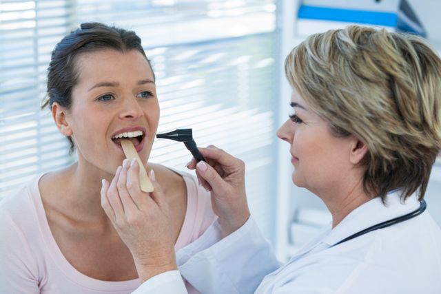 This image shows a doctor using an otoscope to examine a patient's throat in a clinical setting. It can be used for healthcare-related content, medical articles, patient care brochures, and websites focusing on medical services and health checkups.