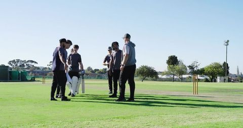 Cricket team walking onto pitch huddling around stumps for pre-match motivation