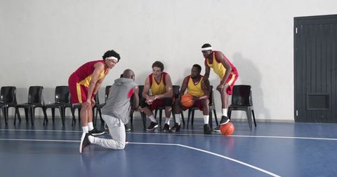 Diverse Basketball Team Receives Coaching Guidance on Indoor Court