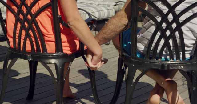 Couple Holding Hands Sitting on Outdoor Chairs at Wooden Deck - Download Free Stock Images Pikwizard.com