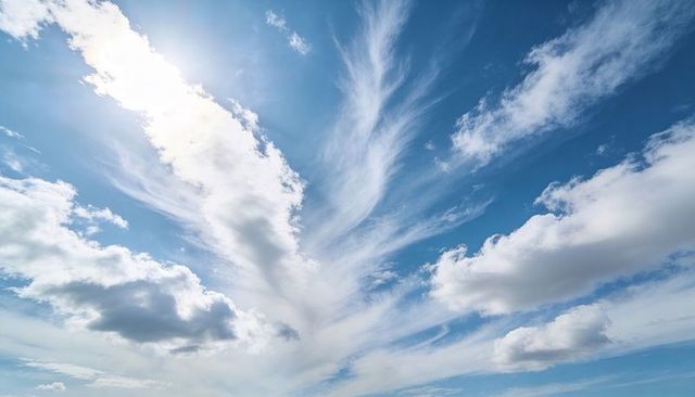 Fanning wispy clouds across blue sky backlit by sunlight, dramatic expansive cloudscape