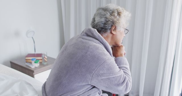 Senior Woman Sitting on Bed Looking Thoughtful by Window in Morning Light - Download Free Stock Images Pikwizard.com