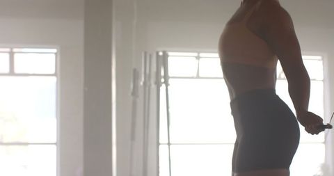 Athletic Woman Jumping Rope for Cardio Workout in Bright Gym